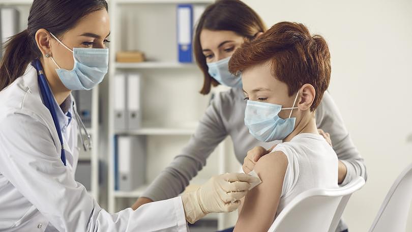 儿童和父母接种流感或 Covid-19 疫苗、大规模疫苗接种和免疫接种的概念。戴着医用口罩的医生给和妈妈一起来医院的小男孩打针