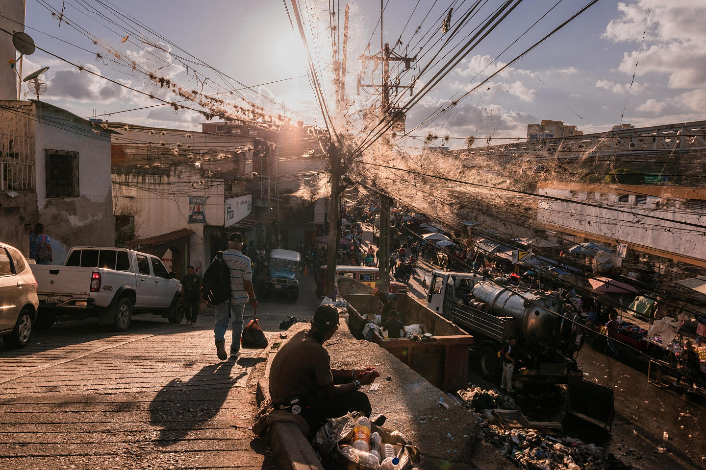 Men scavenge for food in a waste container in a busy street market