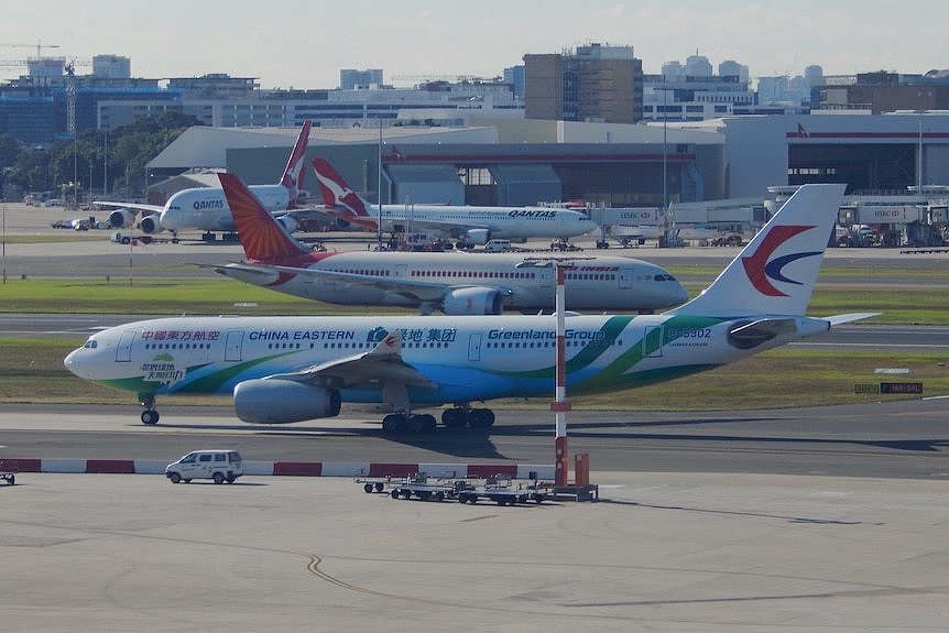 A China Eastern Airlines A330 Airbus sitting on the tarmac at Perth International Airport with other planes in the background.
