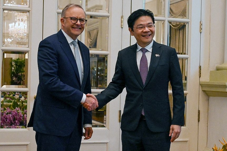 Anthony Albanese and Lawrence Wong pose for photos shaking hands. 