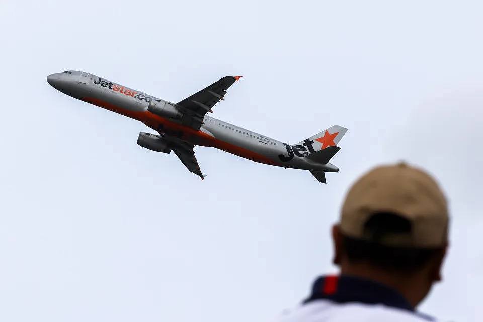 A man looks on from Shep’s Mound, a plane spotters’ lookout as a a Jetstar Airbus A321 takes off from Sydney International airport January 20, 2024 in Sydney.