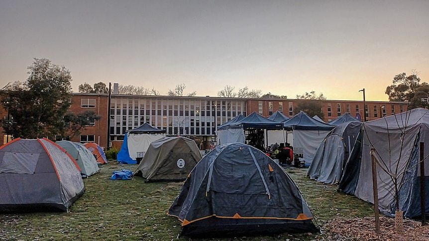 A row of tents in front of a long building at the Australian National University campus.