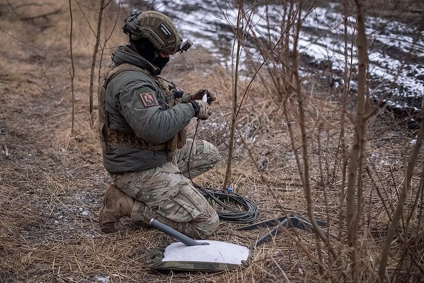 一名乌克兰士兵在前线阵地上准备星链卫星互联网系统。