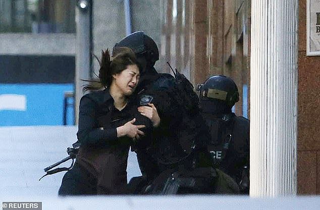 A hostage is pictured running to a police officer outside the Lindt Cafe in Sydney on December 15, 2014