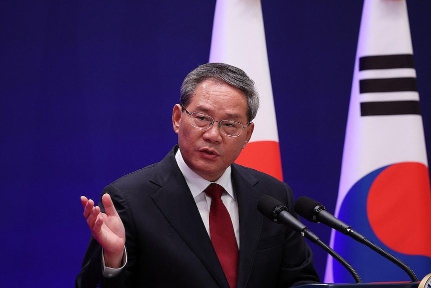Close up of Chinese Premier in a suit speaking behind two microphones