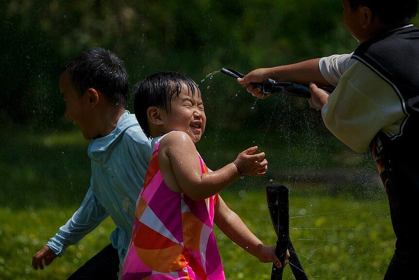 在北京通州，孩子们在烈日下玩水。