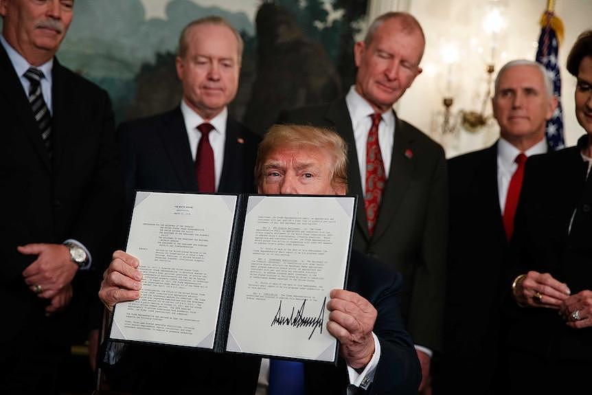 President Donald Trump displays signs a presidential memorandum imposing tariffs and investment restrictions on China.