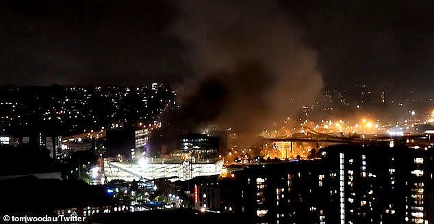 Plumes of smoke could be seen coming out of the tunnel and from the scene of the fire, where several demountables and shipping containers have been burning (pictured)