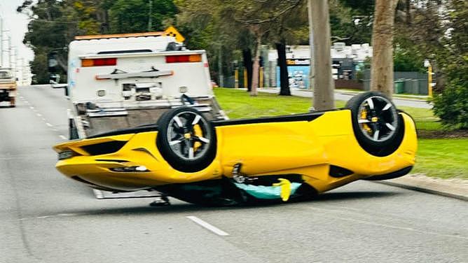 The driver of a luxury car and his passenger are lucky to be alive after flipping a Ferrari on its roof along a busy road.