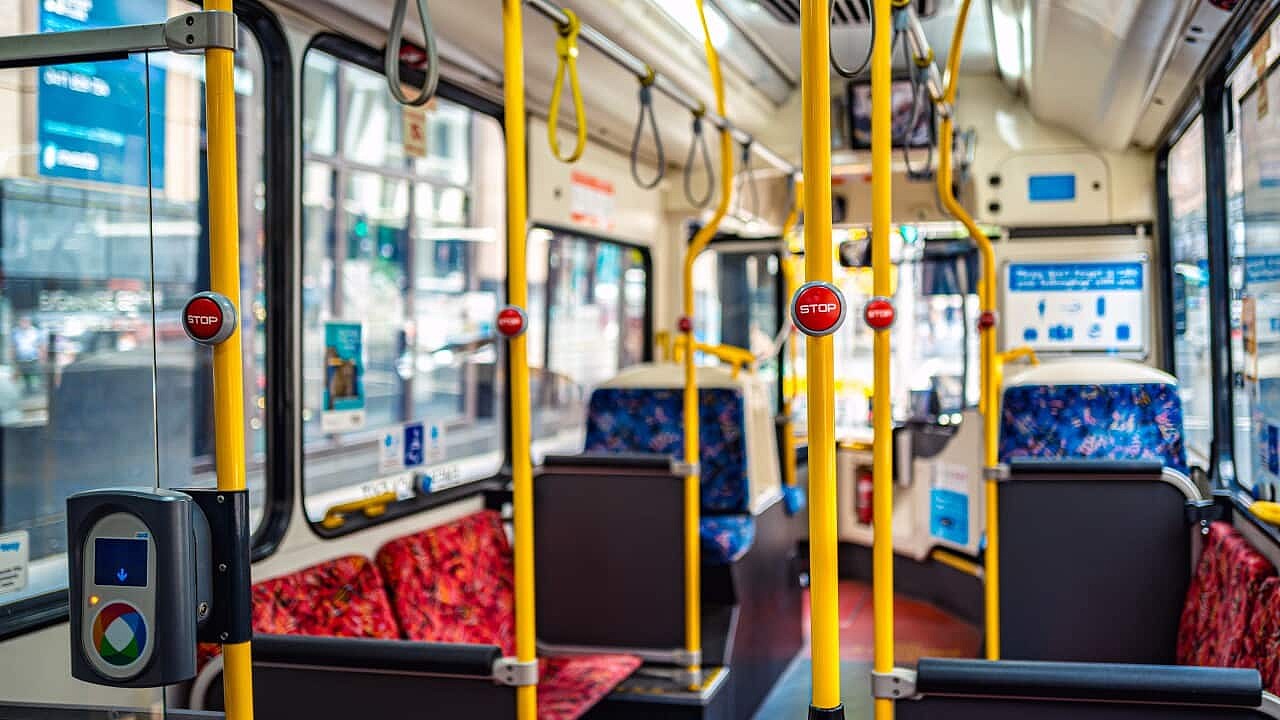 The inside of a bus with bright yellow poles and patterned blue and dark red felt seats.