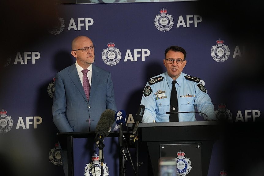 Burgess and Kershaw stand at a lectern speaking.