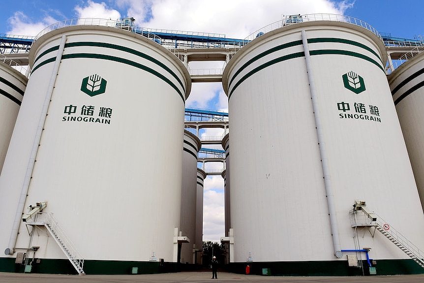 A man cycles past silos.