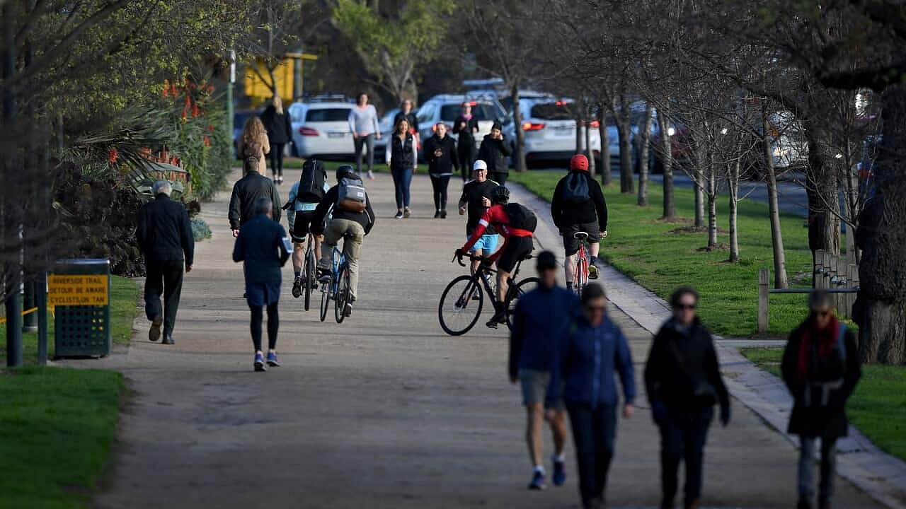 People walking, jogging, and riding bikes along a dirt path.