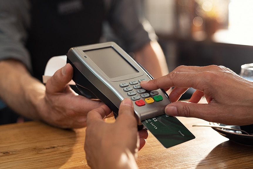 A person inserts a payment card into a terminal at a shop.