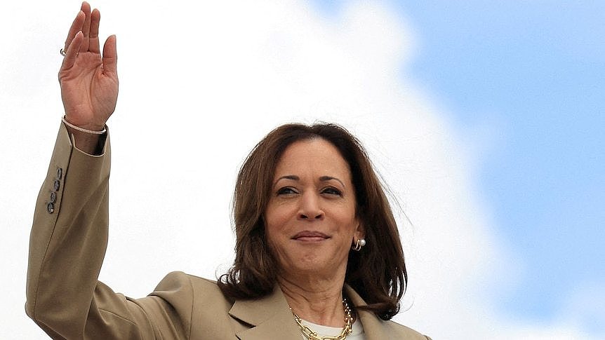 A woman waves in front of a blue sky 