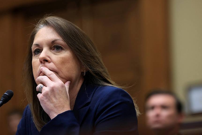 A woman wearing navy blue jacket rests her chin on her hand