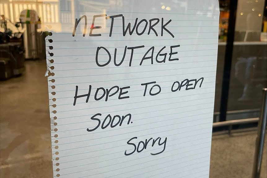 A sign in a window which says Networ Outage hope to open soon