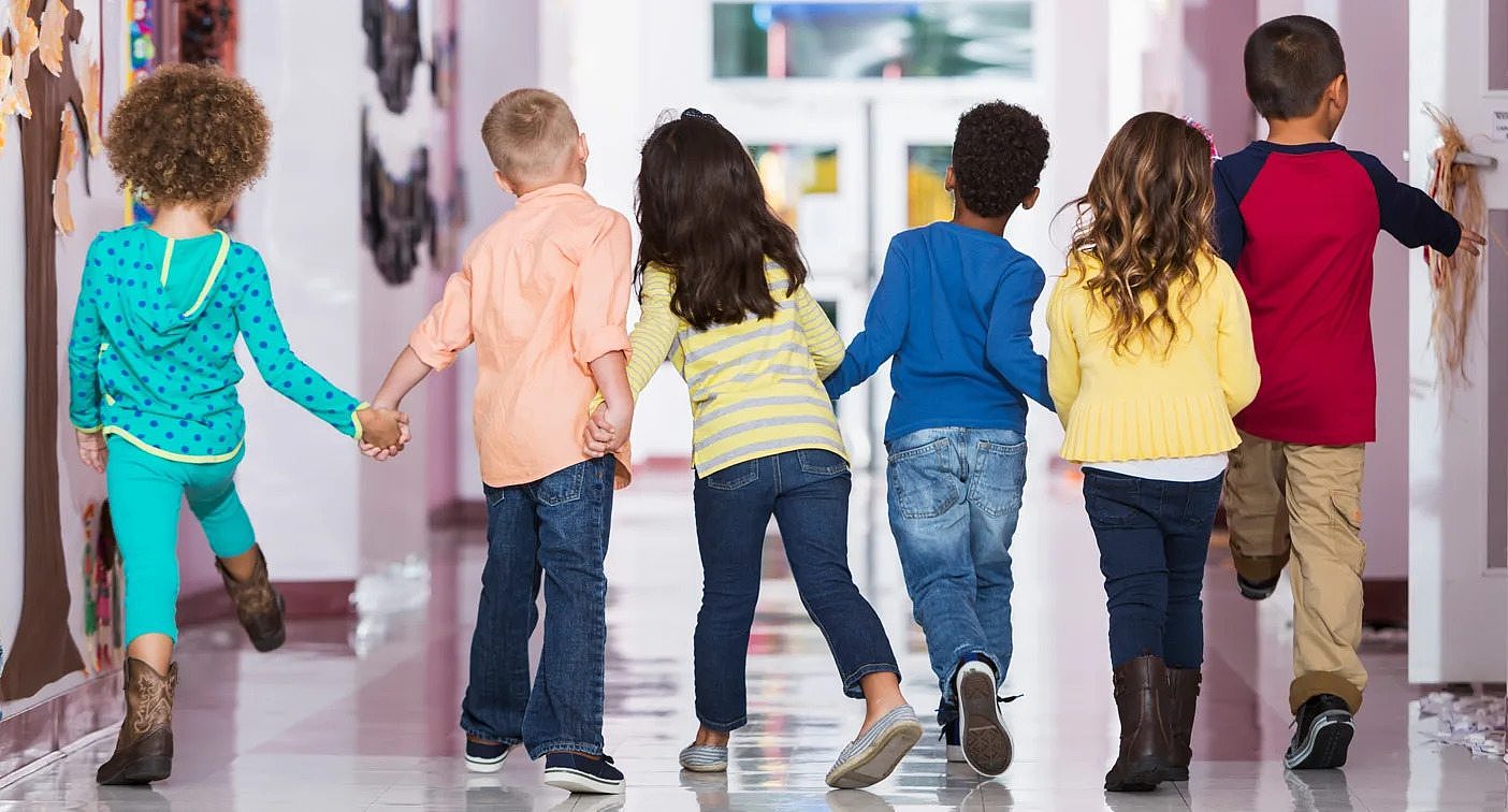 Young children walking in a corridor.