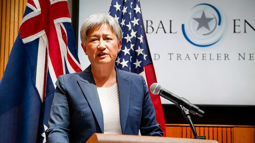 Penny Wong speaks at a podium in front of Australian and US flags.