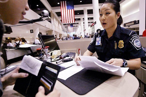 A US Customs and Border Protection officer checks the passport and paperwork of a visitor at Los Angeles International Airport.