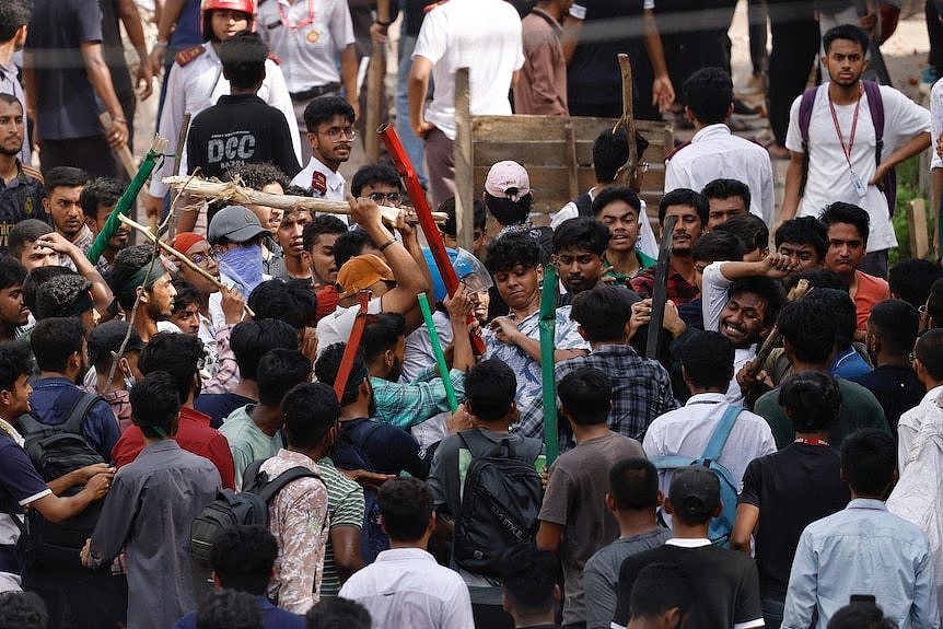 A large mob of people wielding sticks and batons attacks each other 