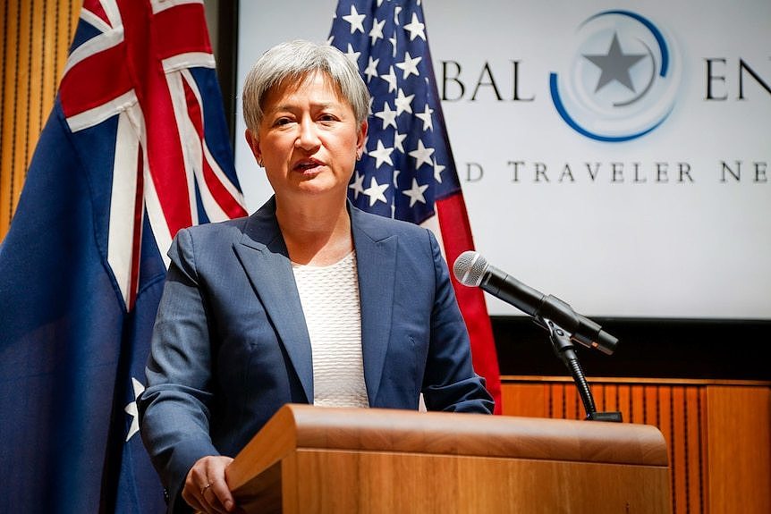 Penny Wong speaks at a podium in front of Australian and US flags.