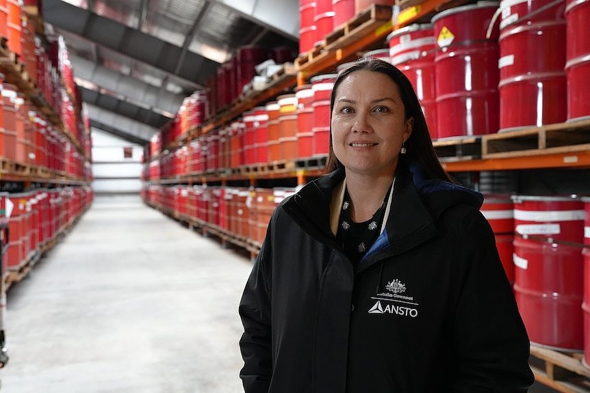 A woman standing in an aisle full of red containers. 