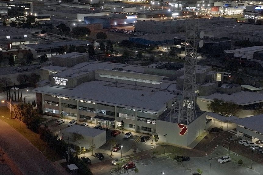 An aerial shot of a large three storey office building. It has a channel 7 logo on it and a tv broadcast tower.