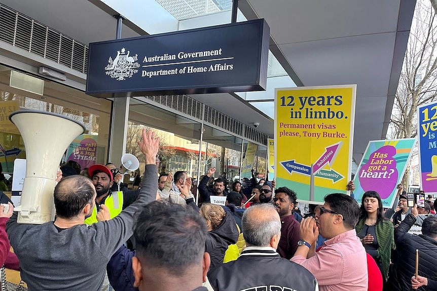 People hold placards and chant outside the Australian Government Department of Home Affairs office