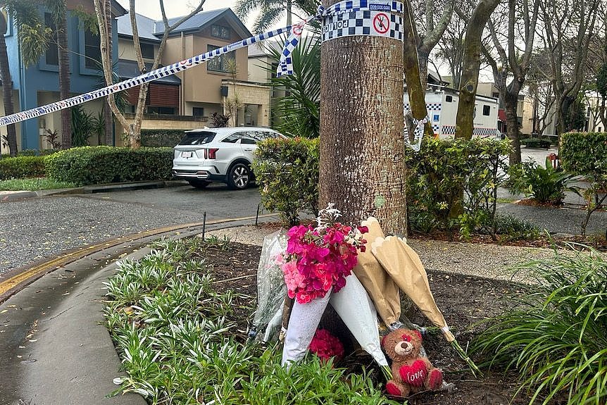 Flowers on ground with police tape. 