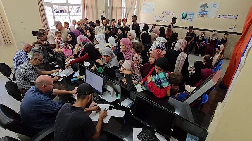 A crowd of people approaching a desk with people sitting behind it.