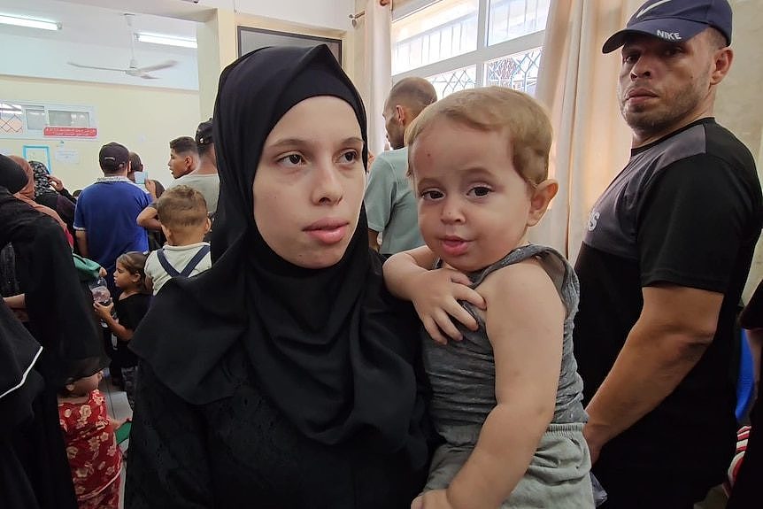 A woman in a hijab carrying a child