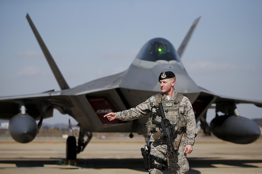 US soldier stands in front of F-22 stealth fighter