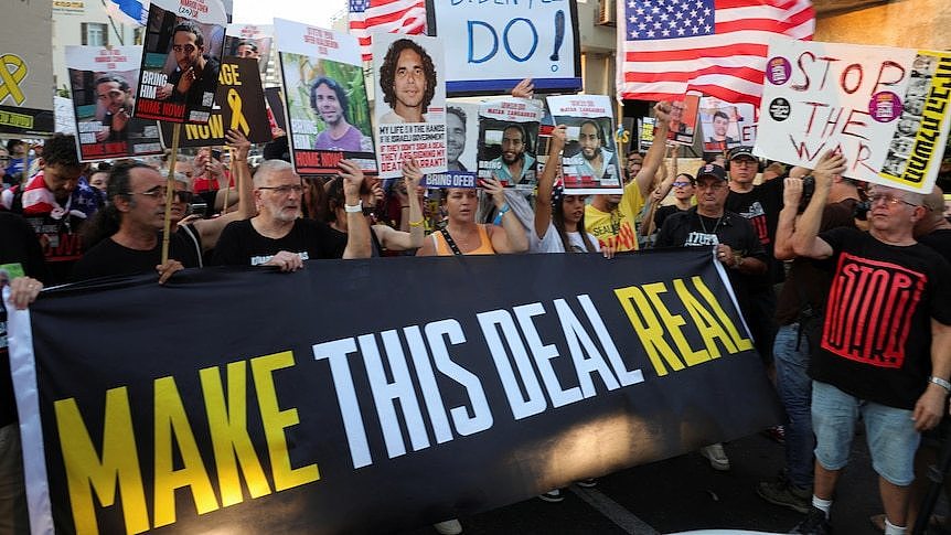 People holding a sign saying make this deal real