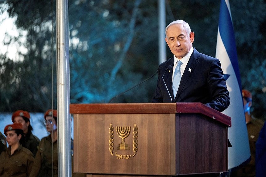 A man wearing a suit stands at a podium