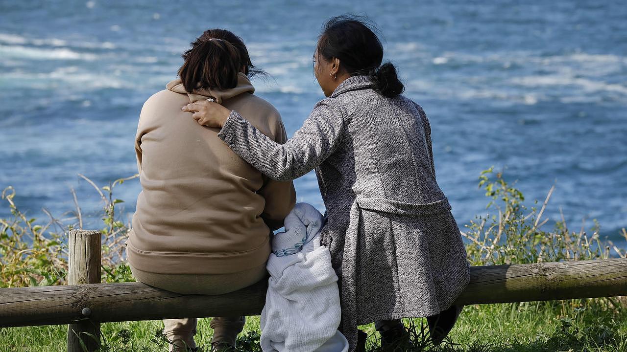 Family being comforted in Kiama. Picture: Richard Dobson