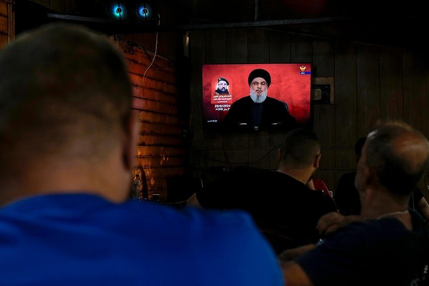 People watching TV in a cafe where Hezbollah leader Sayyed Hassan Nasrallah is giving a speech