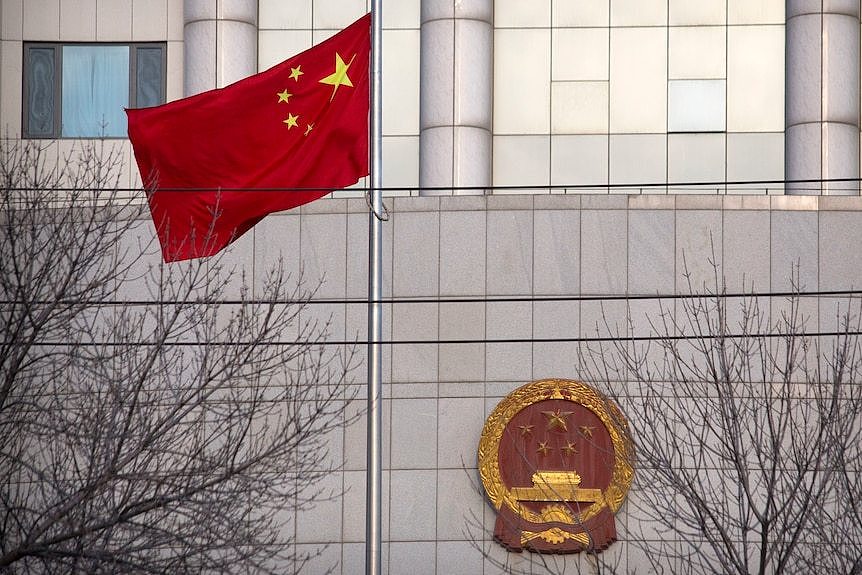 A Chinese flag flies in front of a courthouse in China.