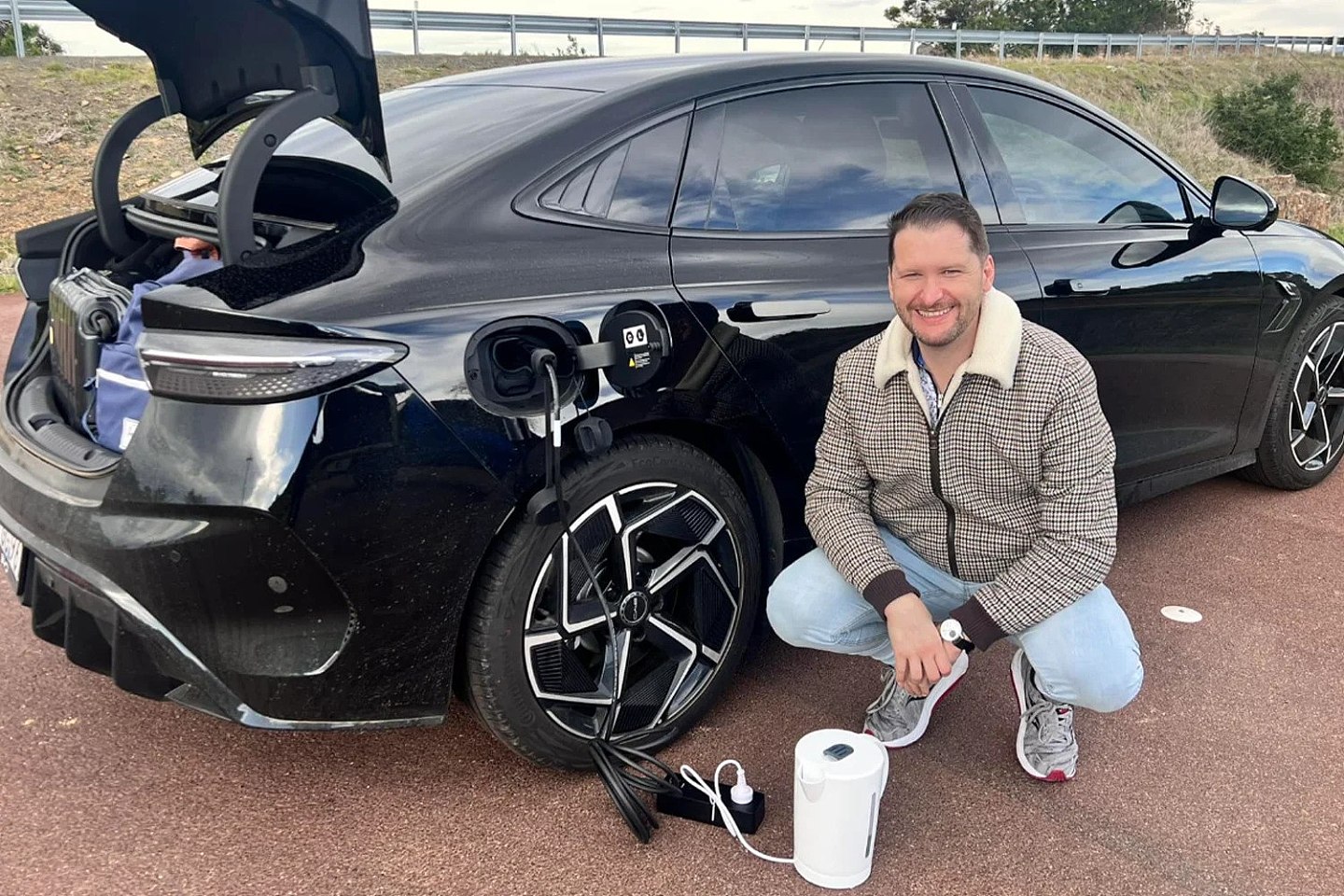 A BYD owner posing while using his car to power his kettle, while on a road trip and away from a traditional power source. 