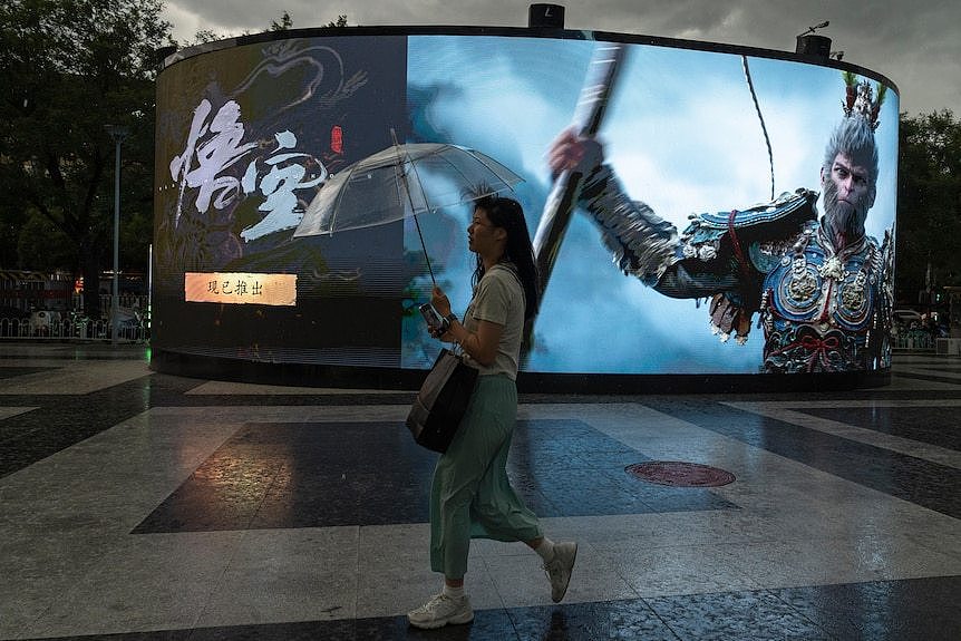 A woman walks past an ad promoting the latest blockbuster new Chinese video game 