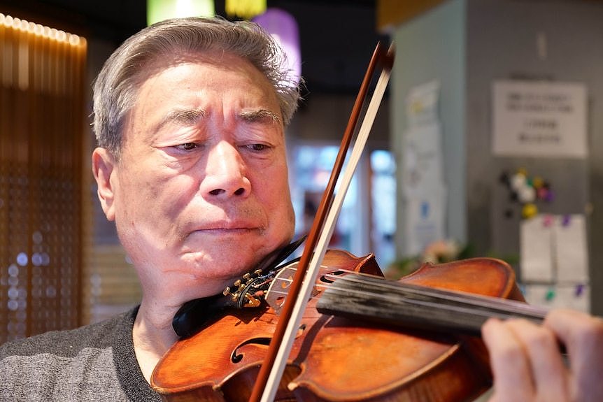 a close up of a man playing a violin