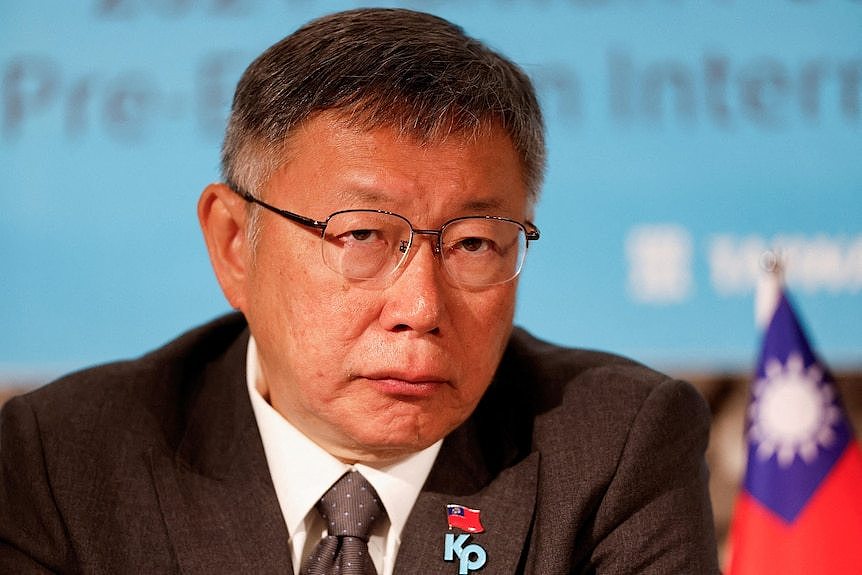 A man in suit with a Taiwan flag in the background.