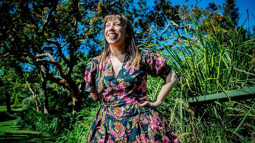 A smiling woman with a floral dress in the sunshine