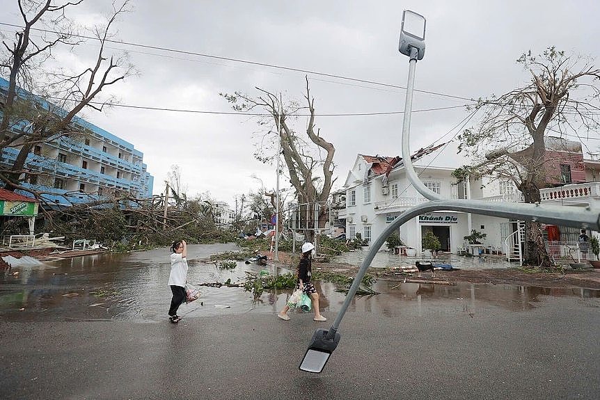 Trees lay in the street and a two-storey property's roof shows significant damage in the aftermath of a storm