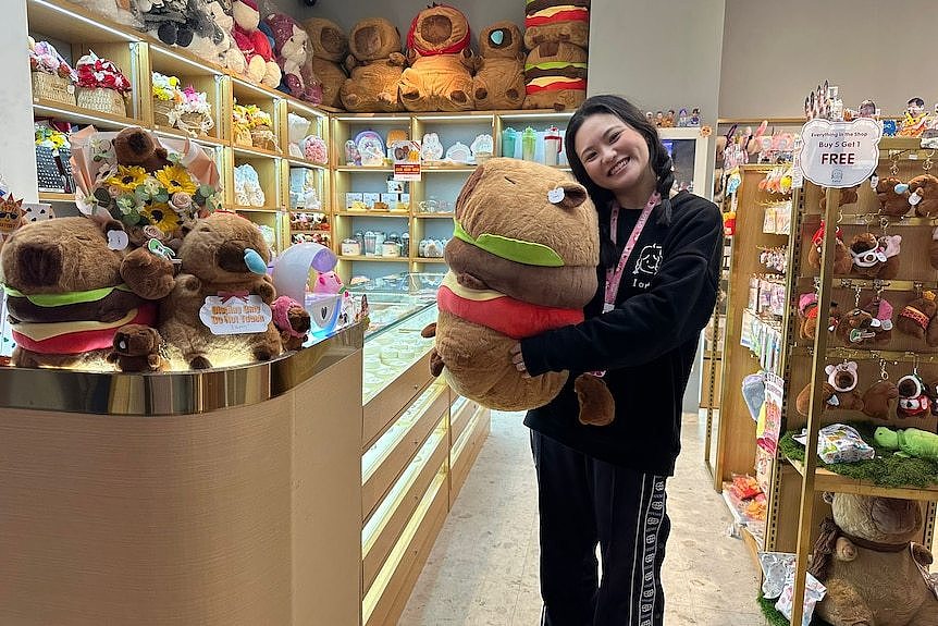 A girl holding a capybara soft toy. 