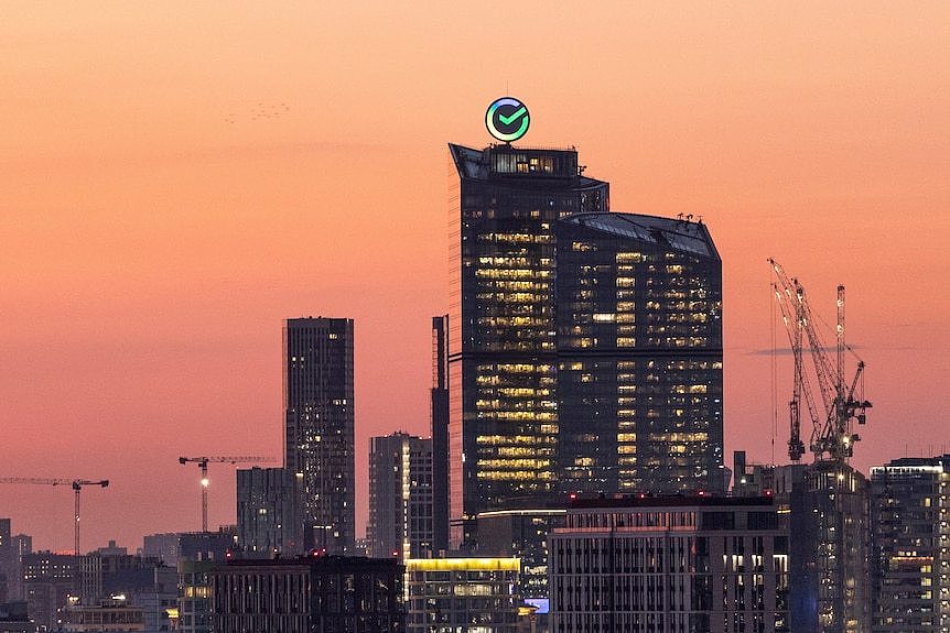 Logo of Russia's biggest bank Sberbank seen along a city skyline at sunset.