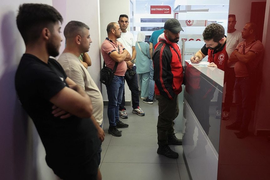 Five men line up to register to give blood at a Red Cross center