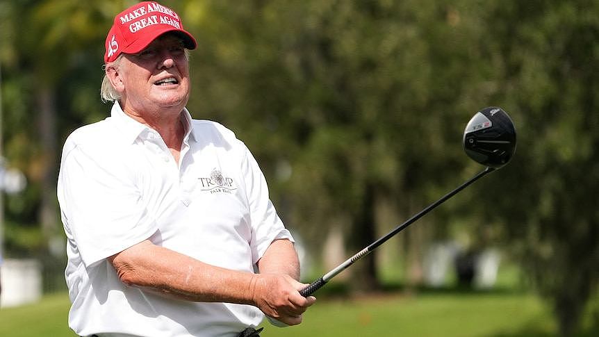 A man in a red cap swings a golf club 