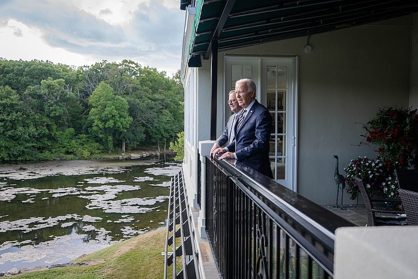 Mr Albanese and Mr Biden stand together on a balcony.