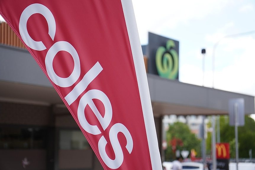 A banner reading 'Coles' and, in the background, the Woolworths logo.